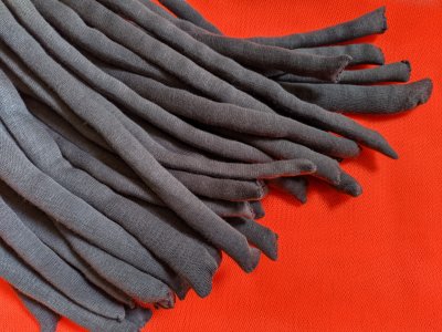 A mass of thick hairlike grey structures piled on top of each other, they have a sway towards the same direction. The background is bright orange.